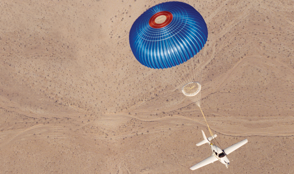 An aircraft descending under its airframe parachute